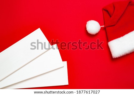Three white wood planks and Santa Claus hat on a red background. Banner with Christmas or new year mood with a free place for text for a hardware store or art shop or business card.