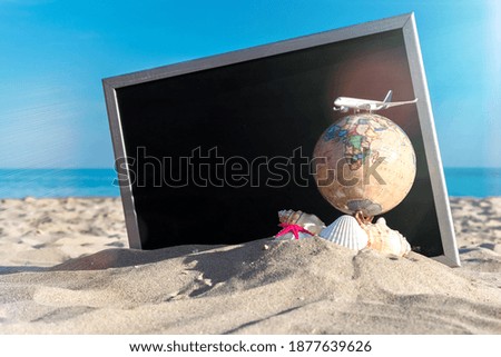 Shell sea. Starfish, seashells, toy plane and globe near blackboard on ocean nature beach. Tranquil beach scene with copy space.