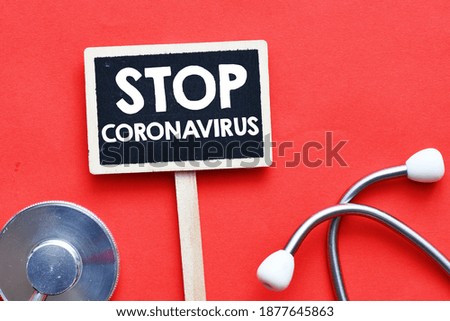 Stop Corona Virus Sign. Text written on a small chalk board, medical stethoscope on a red background