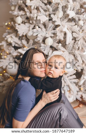 Mom with a small son near a beautiful Christmas tree in his hous