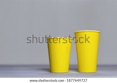 Mockup two yellow paper cups on grey background. Coffee cups and backdrop in the trending colors - ultimate grey and illuminating. Perfect for presentations, decor and web design. Royalty-Free Stock Photo #1877649727