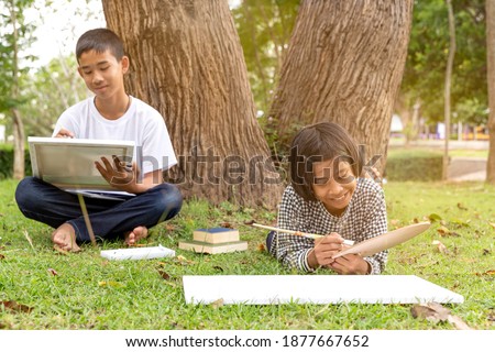 Asian children drawing with painting tools,water color acrylic paint draw together in nature outdoor at park