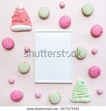 White blank photo frame mockup with various sweets, macaroon, meringues and candies. Flat lay on pink desk