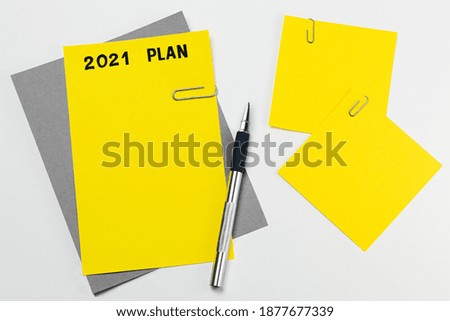 Yellow sheet on gray tablet with hand written plan for 2021. Note sheets for goal setting. Used trending color combinations of 2021 yellow and gray