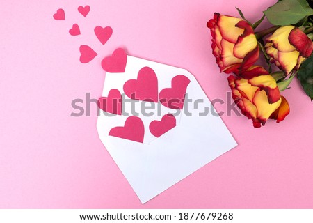 Valentine day idea composition: roses and small red hearts on paper pink background. Top view. Love day concept flat lay.