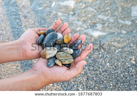 Stones in male's hands near the ocean