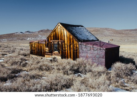 An old, abandoned barn in a meadow in an ancient western ghost town in Northern California at Bodie State Park.