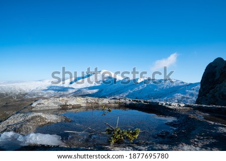 Snowy mountain and puddle on the rock