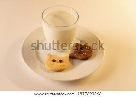 ginger and cocoa cookies on the cat face and a glass of milk. Cat-like cookies and a glass of milk on a white background.