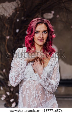 Portrait of a lady in gentle lace peignoir in a dark room with concrete floor and walls