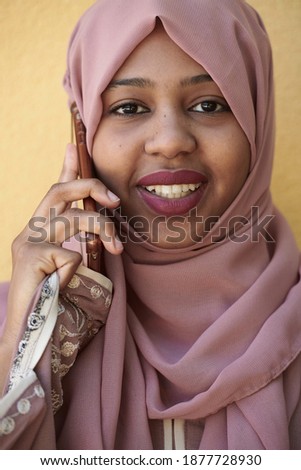 african woman using smartphone wearing traditional islamic clothes
