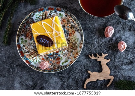Christmas photo of a cake with tea, dried kumquat on a table with fir branches and toys, postcard.