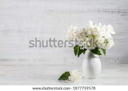 Jasmine flowers in a vase on a wooden background.