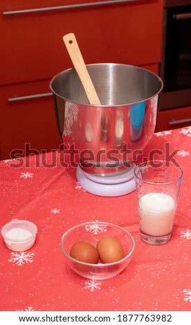 Metal bowl with wooden spoon, glass of milk, eggs. Everything for making dessert for Christmas dinner. Selective focus.