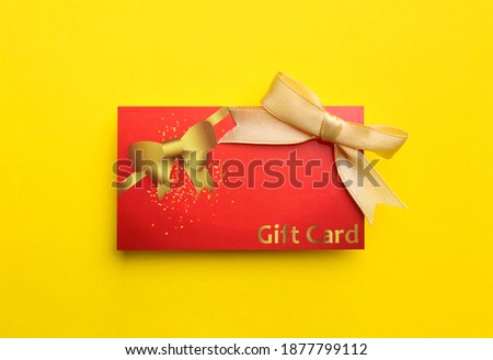 Gift card with bow on yellow background, top view
