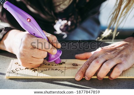 Hand of a woman writing wooden with a pyrography - Burnt wood decoration
