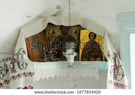 The icon lamp hangs in front of the Iconostasis with icons decorated with embroidered towel and needle lace, next to it lies a bunch of pussy willows for Easter.