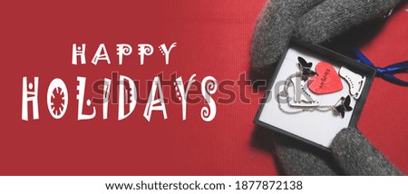 Happy holiday. Hand in winter gloves on a red background with a gift. Theme: winter, new year, christmas. For poster, poster, banner, business card and other design ideas.
