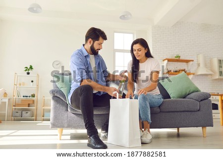 Young married couple received a food delivery and unpacked a package of groceries together. Blank white package with space for text for advertising. Food delivery concept.