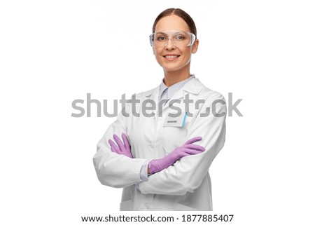 science and profession concept - happy smiling female scientist in goggles and gloves with nametag on lab coat Royalty-Free Stock Photo #1877885407