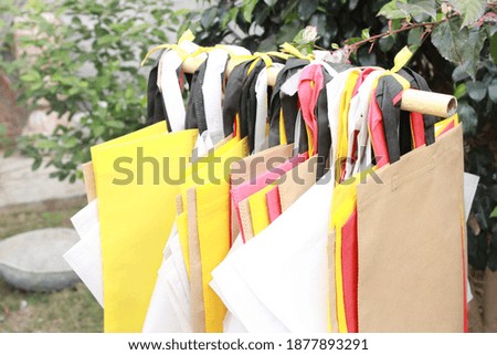 Shopping bags hanging with plant on green garden outdoor. environment friendly concept. clean and green world. stop plastic and use me i am ECO bags new year new shopping with me. Thanks 