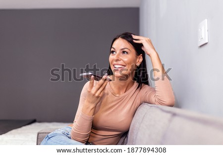 Woman laughing while talking on speakerphone. technology, communication and people concept - happy woman using voice command recorder on smartphone