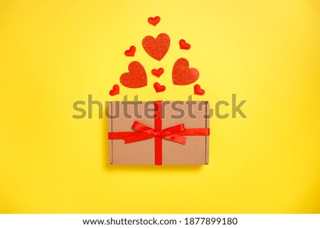 Valentine day greeting card composition. Gift box craft paper with hearts on yellow background. Top view,flat lay, copy space