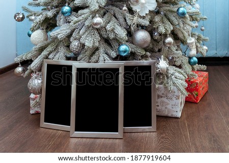 Silver photo frames or certificates under the Christmas tree with gifts