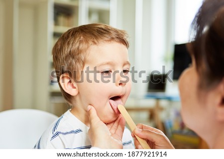 Pediatrician examines tongue of a child with tonsillitis with a spatula Royalty-Free Stock Photo #1877921914