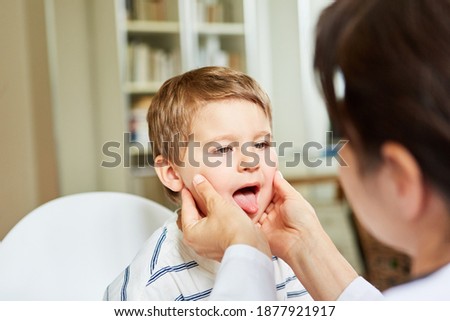 Female doctor examines throat and tongue in child with tonsillitis or sore throat Royalty-Free Stock Photo #1877921917