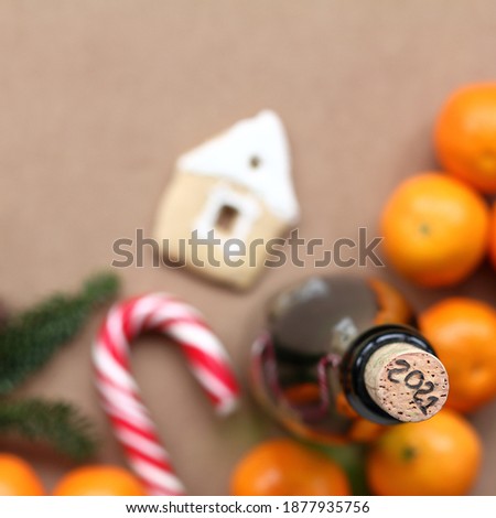 date 2021 on a wine cork in a bottle against the background of a blurred table silhouette with tangerines, figured cookies, christmas tree and striped candy top view. opening of the year