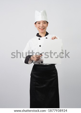 Woman wearing chef uniform or cooker and holding blank A4 paper on white background.