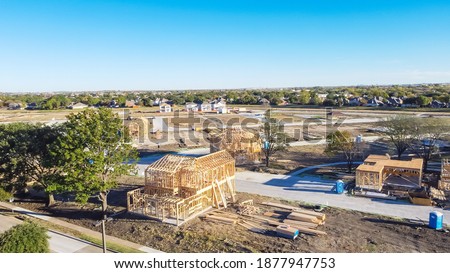 Aerial view wooden houses under construction in master planned community suburbs Dallas, Texas, America. Typical two story single family home on slab foundation