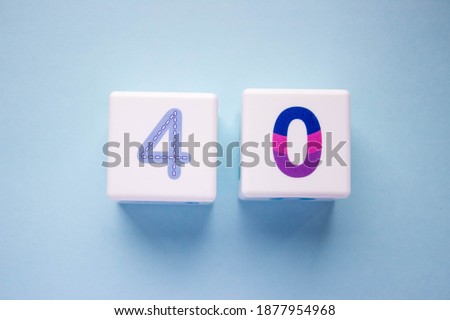 Close-up photo of a white plastic cubes with a colorful number 40 on a blue background. Object in the center of the photo Royalty-Free Stock Photo #1877954968