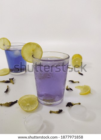 Noised, selective focus and blurred photo of lime, dried butterfly pea flower and a cup of Herbal Drink (Es Bunga Telang). 