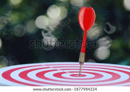 close up red arrow hitting on target center of dartboard, green nature copy space background for text, sport and recreation, planning and manage to success business concept