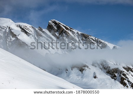 White peak of mountain with fog and dense snow cover.