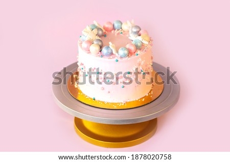 New Year's festive Christmas cake on a stand on a pink background. Christmas sweets decorated with New Year's decor and berries.