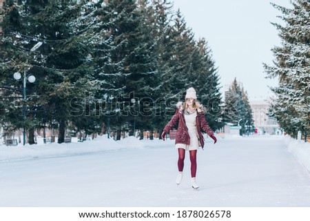 Young blonde girl skating in snowy winter park. Winter holidays concept