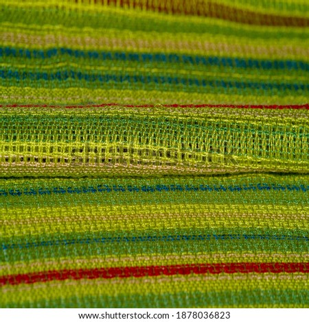 abric of light green color with stripes of red-blue-yellow lines, very light elastic knitwear, light sheen. texture background, pattern postcard