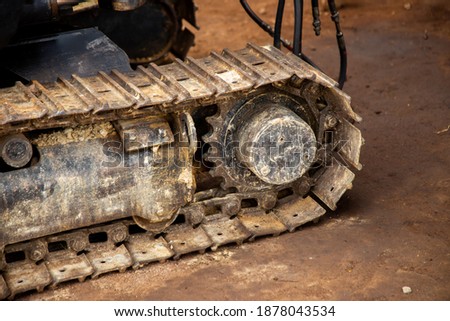 
The undercarriage part of a backhoe. The wheel of a backhoe. Dirty wheel of a backhoe.  Royalty-Free Stock Photo #1878043534