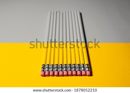 several pencils on a two-color background yellow and gray