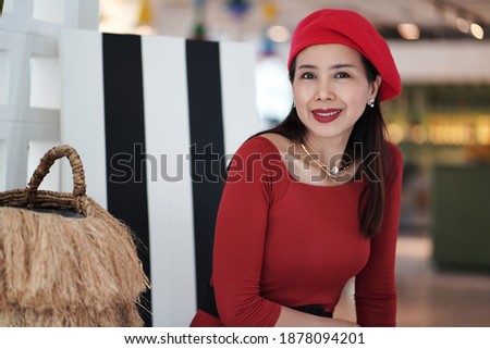 Beautiful woman in Red dress wearing a hat sitting in the Coffee shop,Positive emotions.