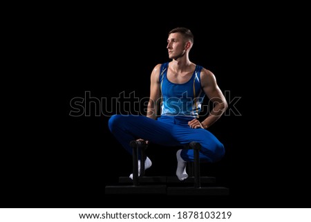 Target. Muscular male gymnast training in gym, flexible and active. Caucasian fit guy, athlete in blue sportswear doing exercises for strength, balance. Movement, action, motion, dynamic concept.