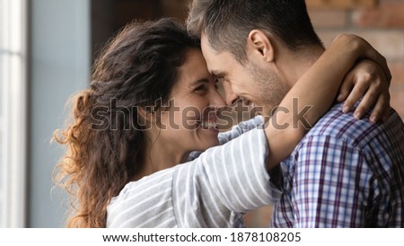 Love in your eyes. Loving millennial woman embracing neck of beloved man with warmth care. Happy wife girlfriend looking in husband boyfriend eyes smiling touching forehead share affectionate feeling Royalty-Free Stock Photo #1878108205