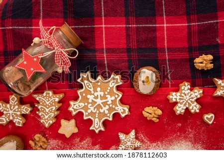Tasty homemade Christmas cookies red background. Windows background with Christmas cookies. Various shapes in sugar glaze. Composition with gingerbread cookies. Snow from icing sugar. 
Powdered sugar 