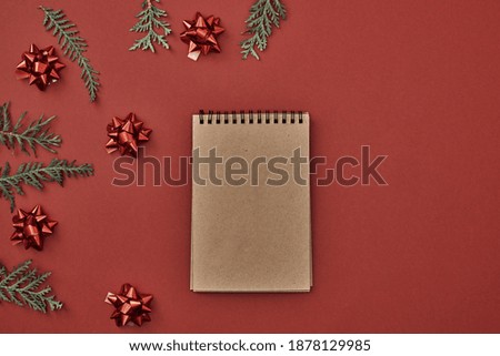 New Year's decor and a notebook in the center on a red background. Christmas decoration. Copy space, flat lay, mock up, top view.