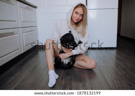 Girl playing with a black pug dog on the floor