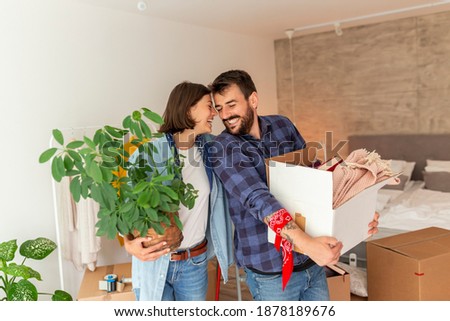 Young couple in love moving in together, having fun while carrying cardboard boxes with their stuff and setting up the new apartment Royalty-Free Stock Photo #1878189676