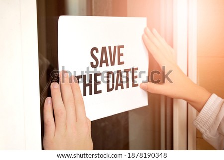 Closeup of owner holding text Save the Date in store